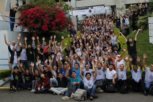 Decenas de personas levantan las manos con alegría, mientras posan para la foto oficial de Drupal Camp en 2015